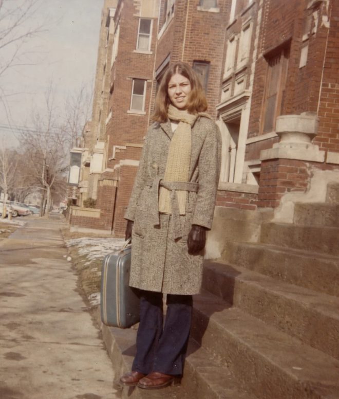 A young woman with a suitcase outside a Chicago apartment building in winter